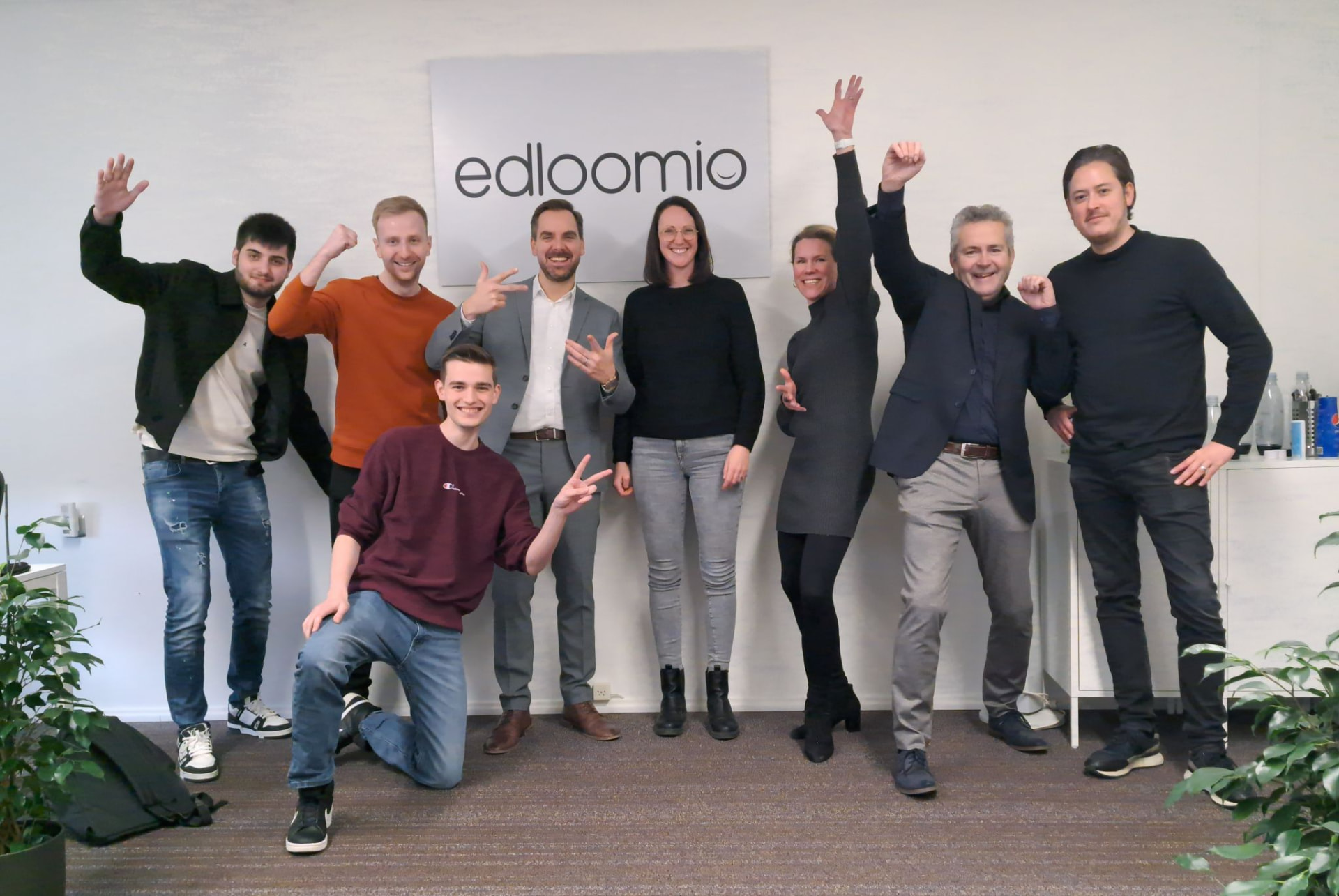 The Edloomio team celebrating in 2023, in front of the Edloomio logo